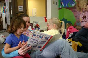 A student volunteer reads to children at the Child Development Center Laboratory